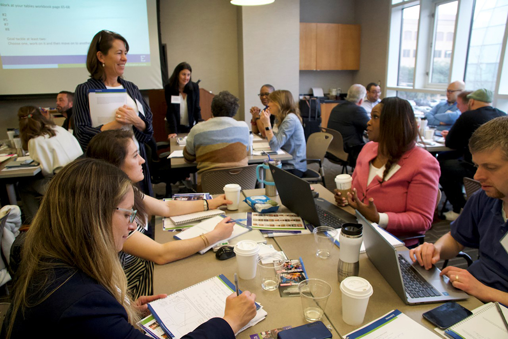 Marguerite Roza, Ph.D. engages with attendees working at tables during a training.