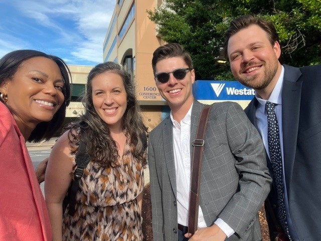 Four R14CC team members smile for a selfie outside.