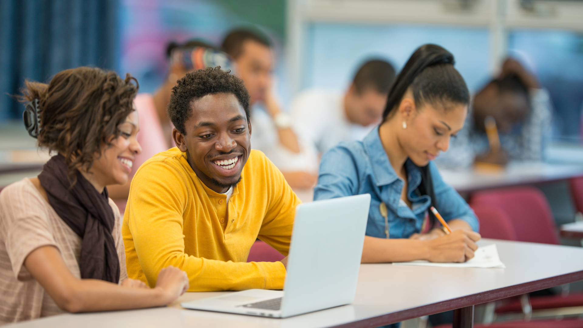 Students smiling while looking at a laptop
