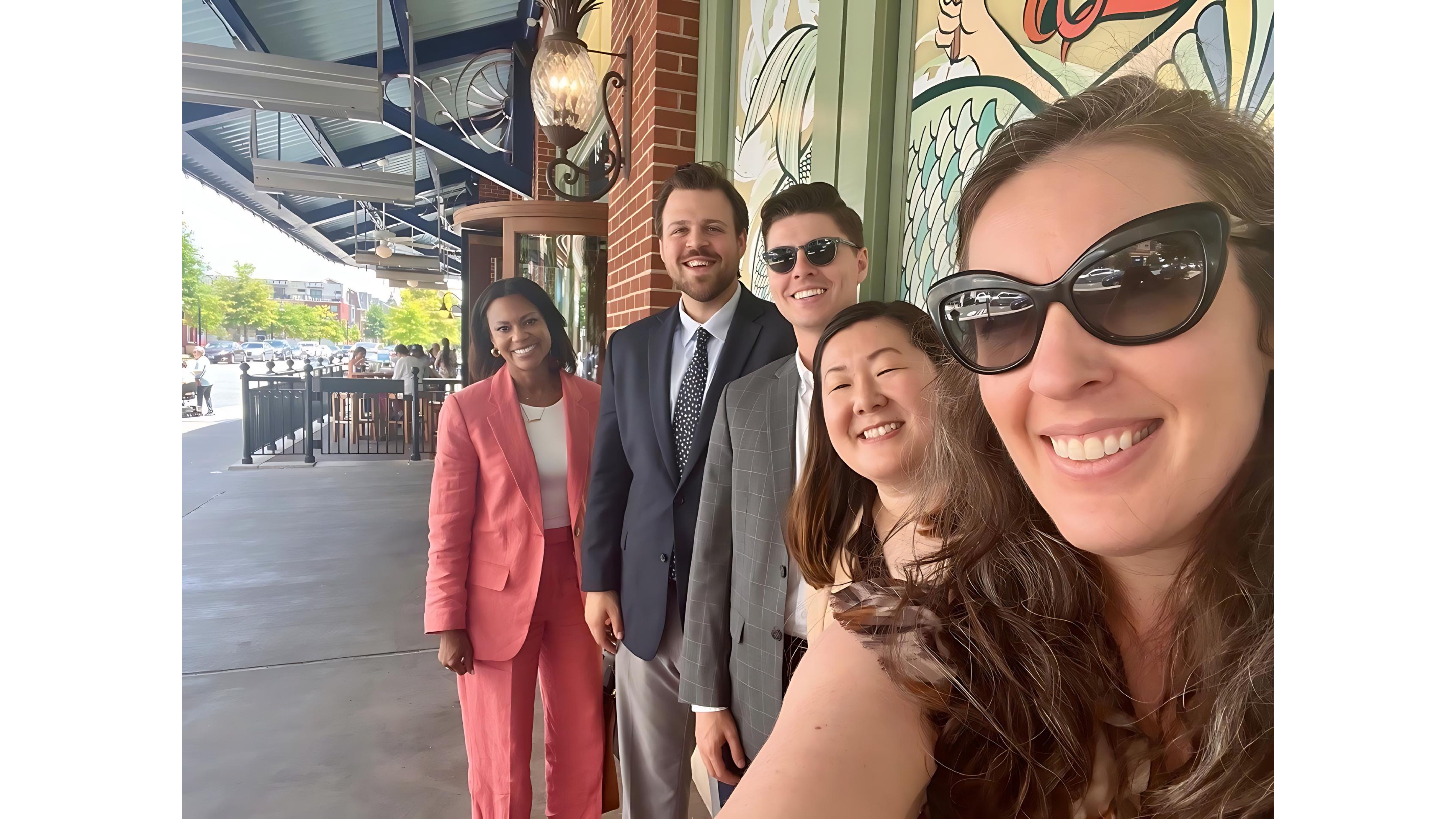 Five professionals smile for a selfie 